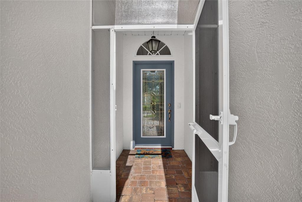 A blue front door with a glass insert sits behind a screen door on a patio — 2222 MAYFIELD PALMS LANE UNIT 322, SUN CITY CENTER, FL