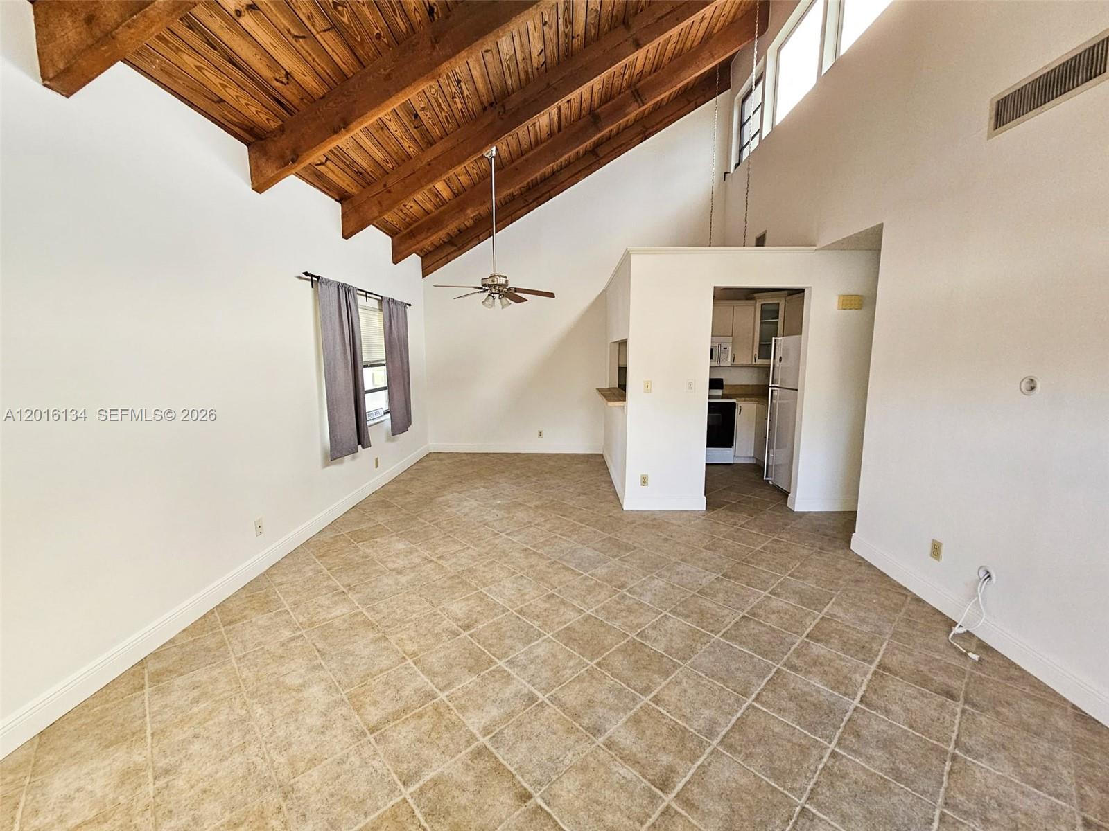 An open living area features a vaulted wood-beamed ceiling, tile flooring, and an adjacent kitchen — 7749 SW 100th St # 33, Miami FL 33156, MIAMI, FL