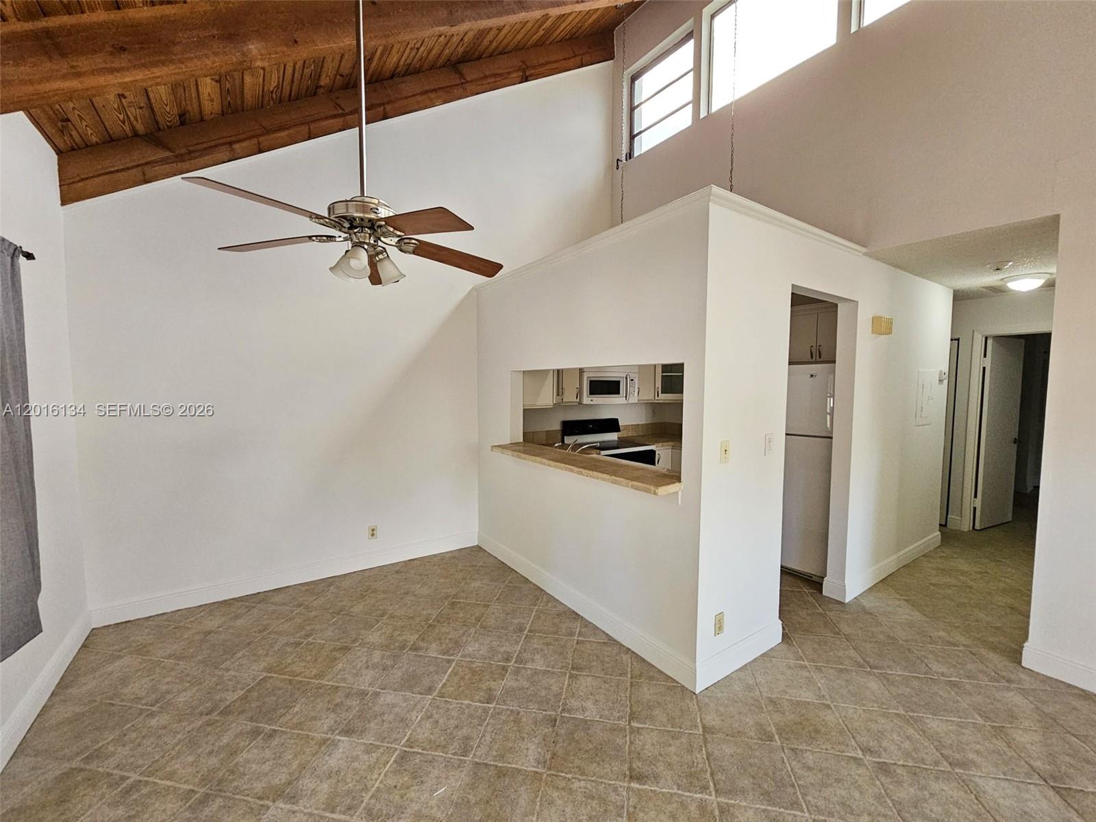A room with a vaulted wood-paneled ceiling, tile flooring, and a kitchen pass-through window — 7749 SW 100th St # 33, Miami FL 33156, MIAMI, FL