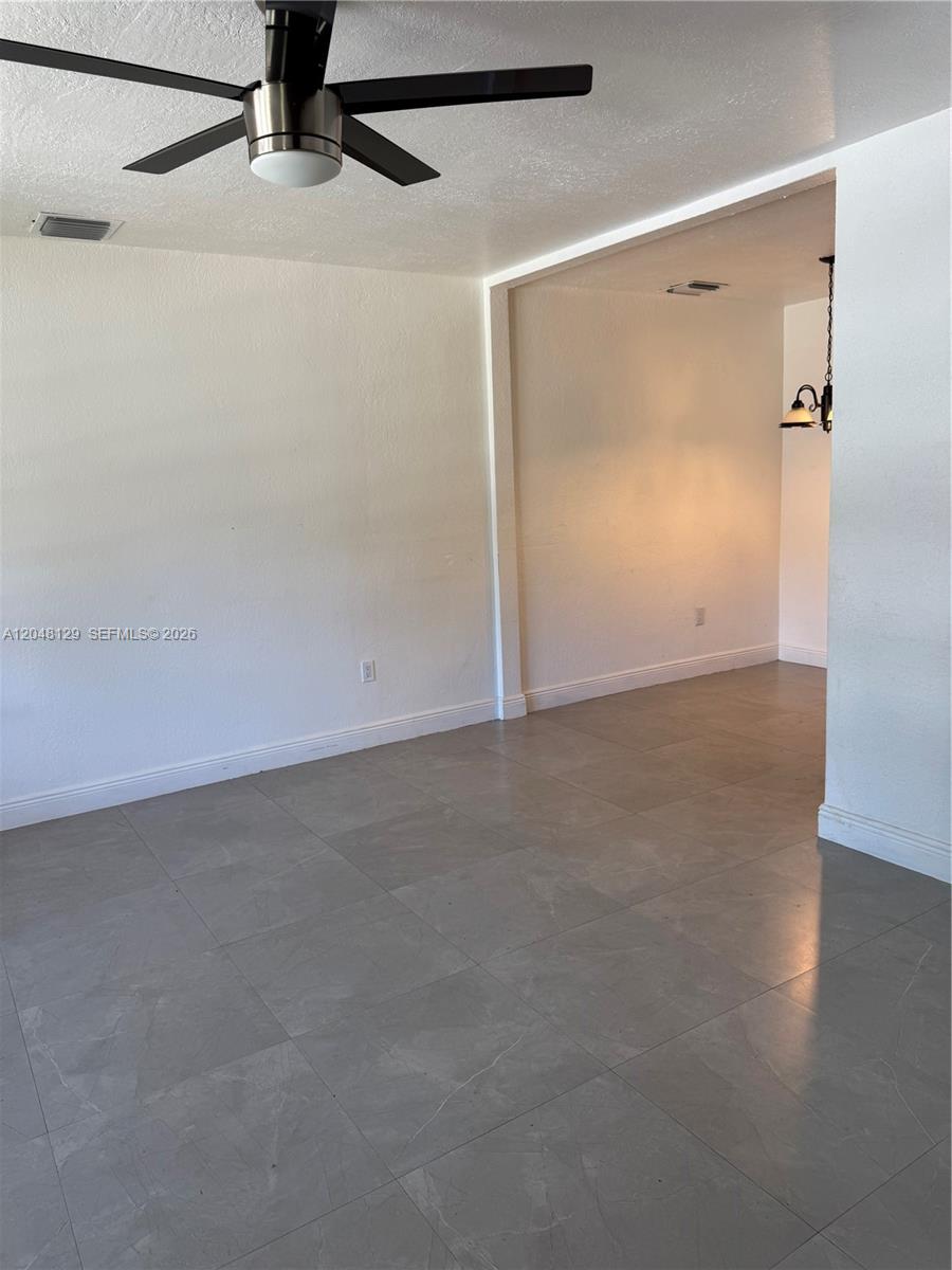 An empty room with gray tile flooring, white walls, and a ceiling fan — 1281 NE 209th Ter, Miami FL 33179, MIAMI, FL