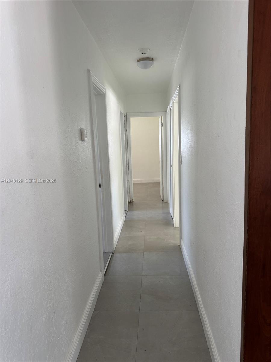 A narrow hallway features white walls, gray tile flooring, and several closed interior doors — 1281 NE 209th Ter, Miami FL 33179, MIAMI, FL