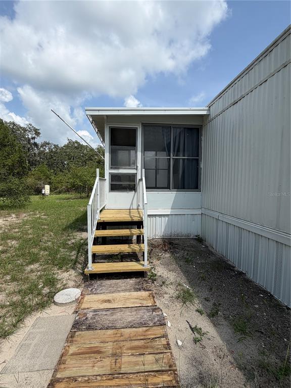 A mobile home exterior features a screened-in porch with wooden steps and a wooden walkway — 5270 W GLENBROOK STREET, HOMOSASSA, FL