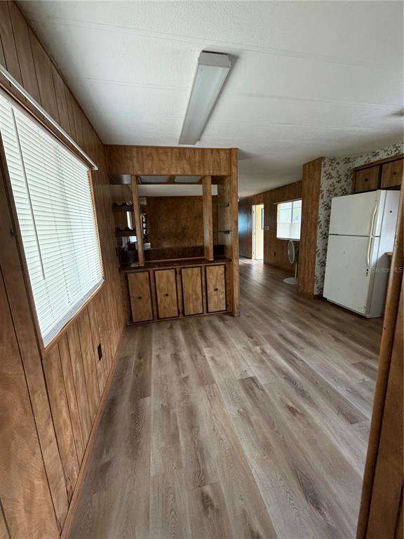 A room with wood-paneled walls, wood-look flooring, a built-in bar area, and a white refrigerator — 5270 W GLENBROOK STREET, HOMOSASSA, FL