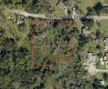 An aerial map view shows a vacant, wooded lot outlined in red near a street — 0 WASHINGTON STREET, NEW SMYRNA BEACH, FL