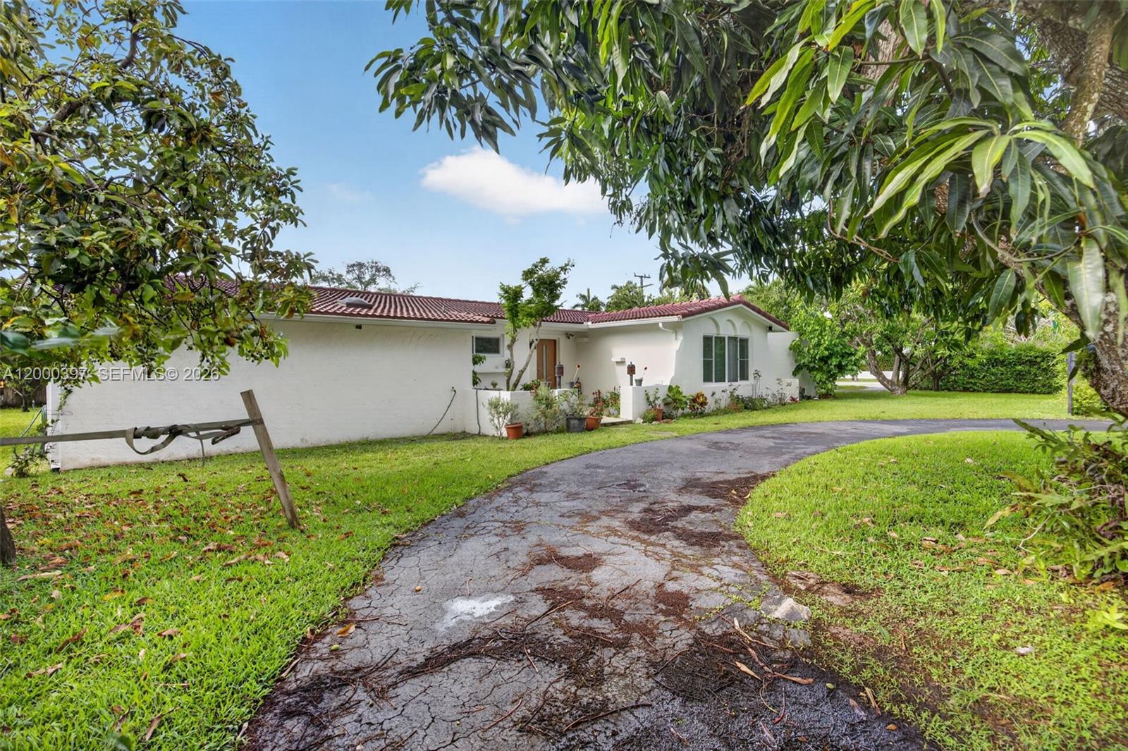 A white single-story house with a red tile roof and a cracked asphalt driveway — 7690 SW 128th St # 0, Pinecrest FL 33156, PINECREST, FL