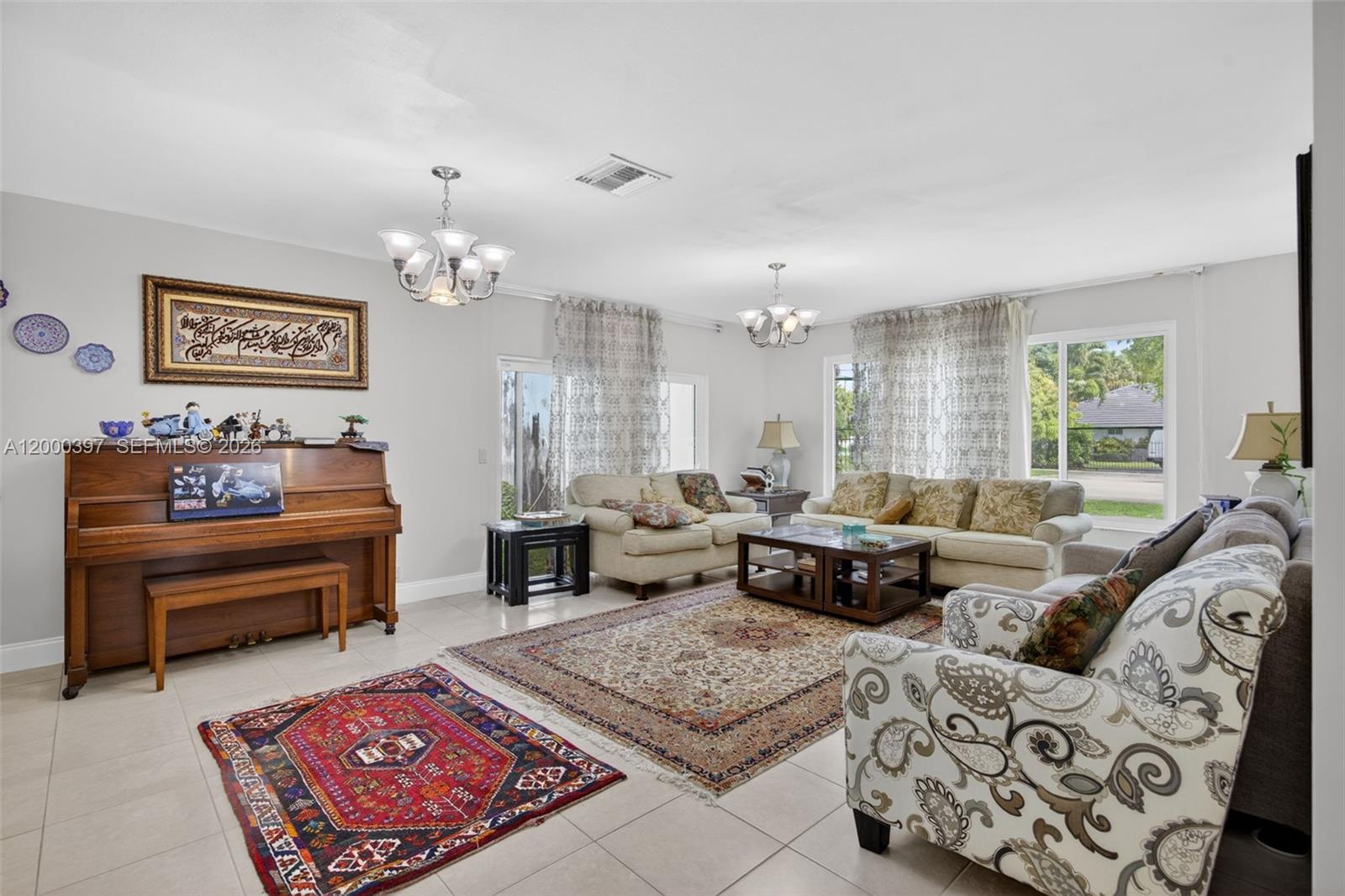 A living room features a piano, multiple seating areas, two chandeliers, and patterned area rugs — 7690 SW 128th St # 0, Pinecrest FL 33156, PINECREST, FL