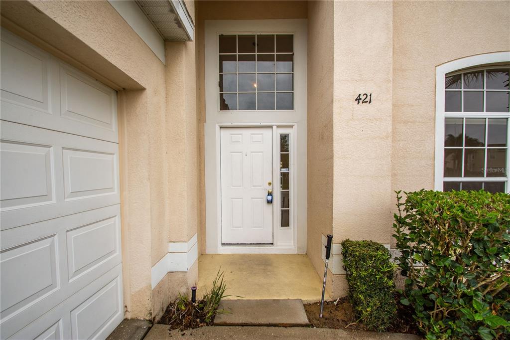 The exterior of a house features a white front door, garage, and arched window — 421 LOCKBREEZE DRIVE, DAVENPORT, FL