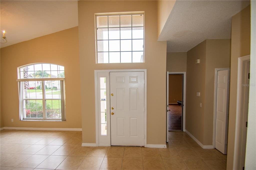 A bright entryway features tile flooring, a high ceiling, and a large front door — 421 LOCKBREEZE DRIVE, DAVENPORT, FL