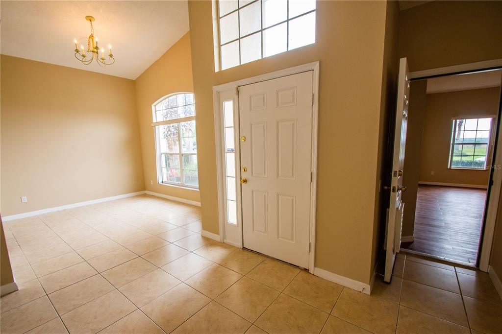 An entryway with beige tile flooring, a white front door, and a vaulted ceiling — 421 LOCKBREEZE DRIVE, DAVENPORT, FL