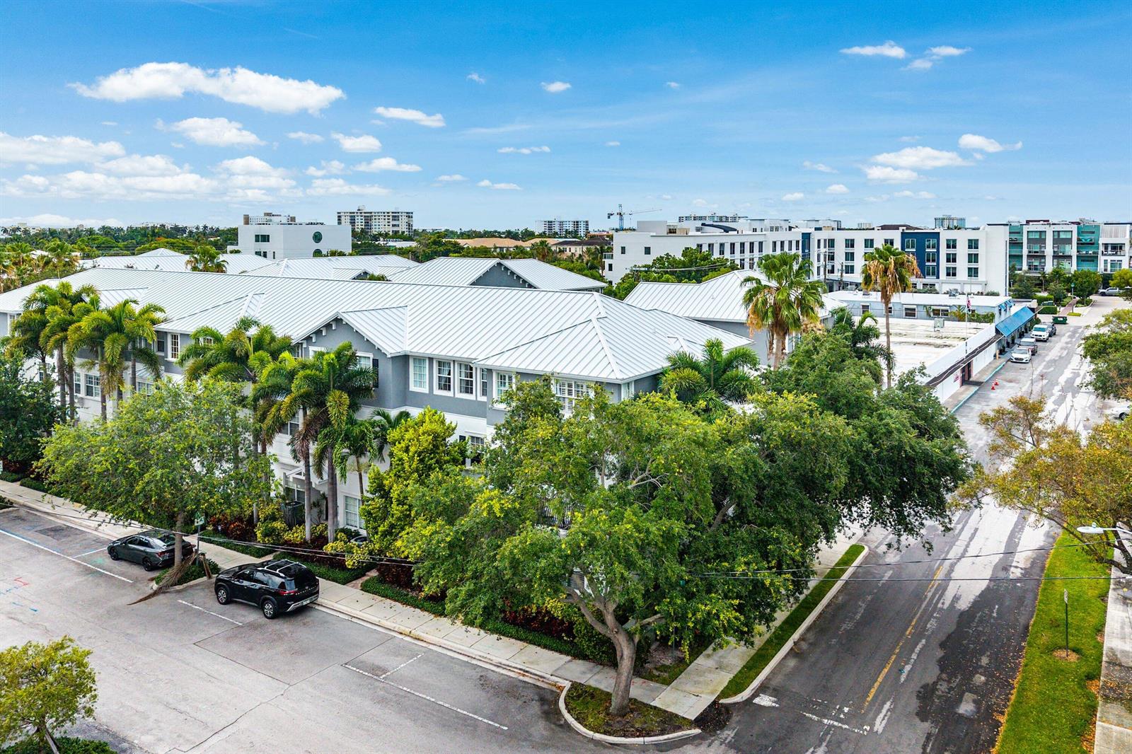 A white multi-story townhouse with a balcony stands behind a large tree and landscaping — 290 NE 5th Avenue # 9, Delray Beach FL 33483, DELRAY BEACH, FL