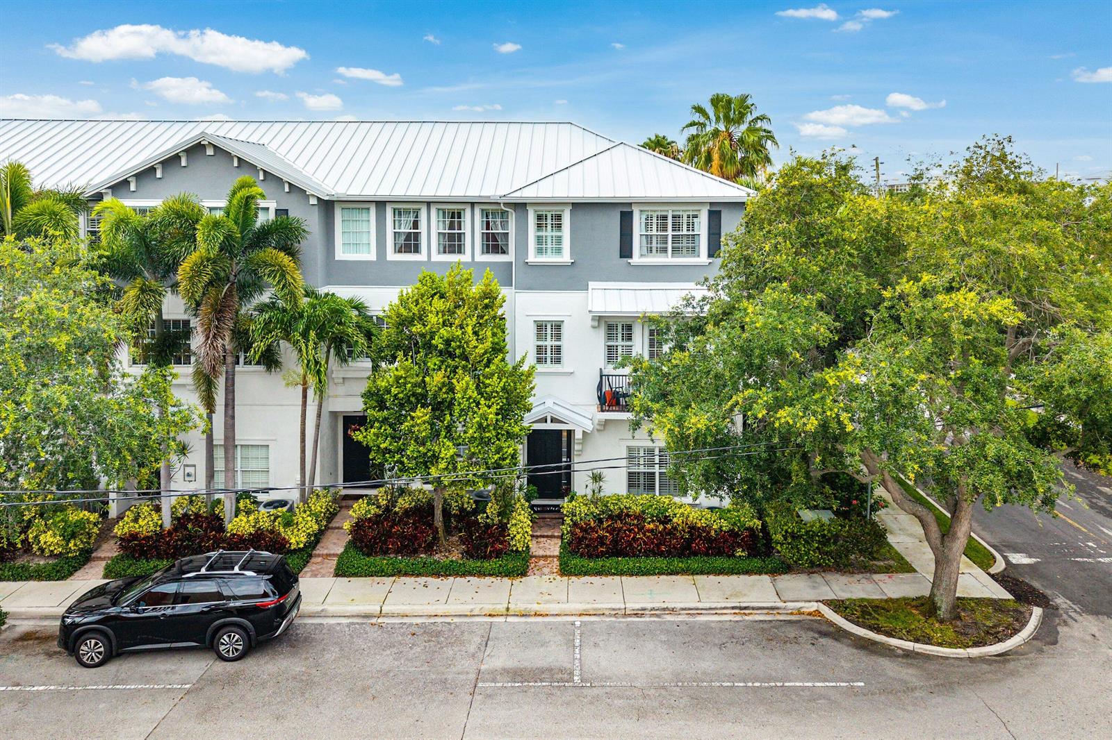 A three-story townhouse with a white metal roof, gray and white exterior, and palm trees — 290 NE 5th Avenue # 9, Delray Beach FL 33483, DELRAY BEACH, FL