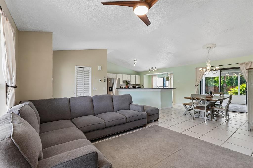 A living room with a gray sectional sofa opens to a kitchen and dining area — 6805 LONGPOINTE WAY, TAMPA, FL