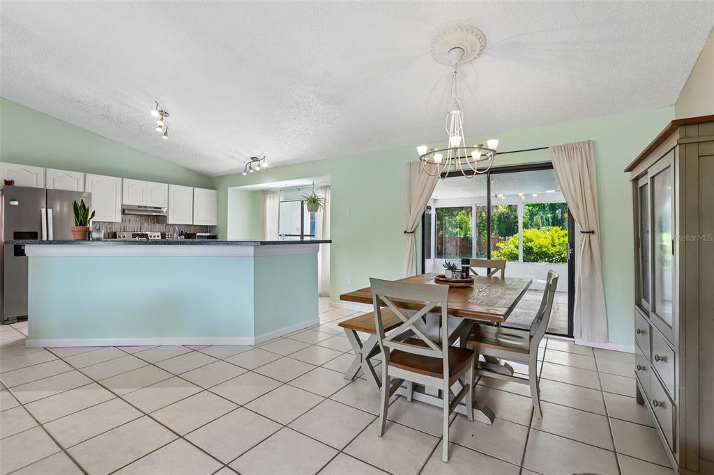 A dining area with a wooden table and chairs sits adjacent to an open kitchen — 6805 LONGPOINTE WAY, TAMPA, FL