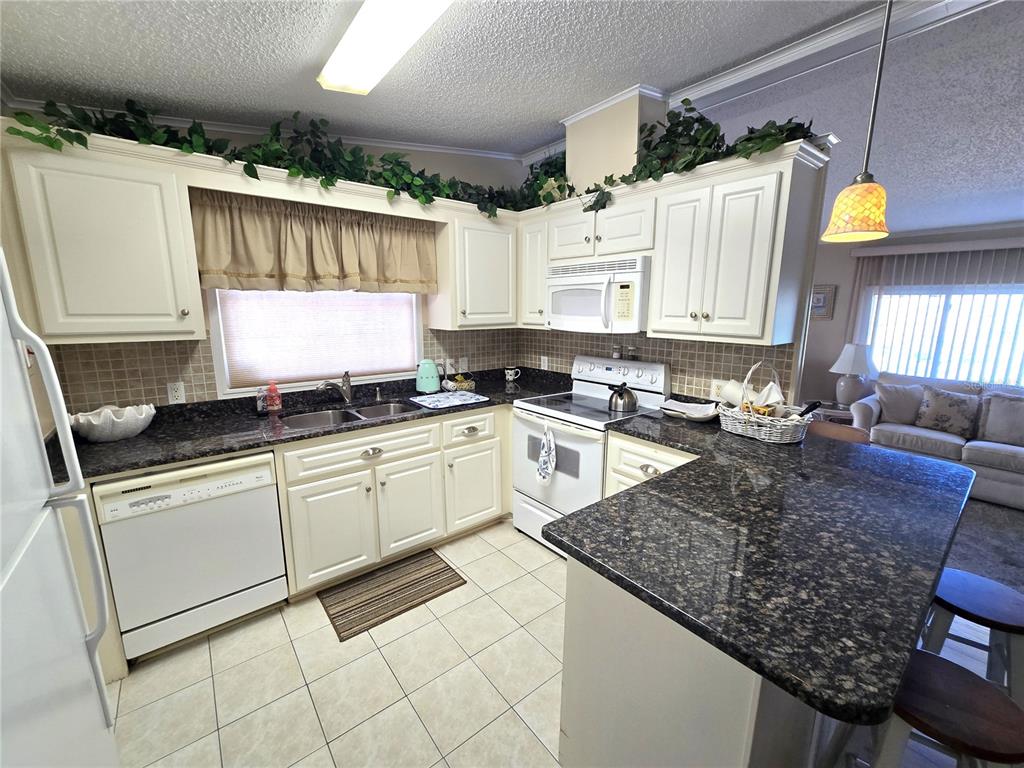 A kitchen with white cabinets, dark granite countertops, and tile flooring — 8503 PRINCESS COURT, PALMETTO, FL