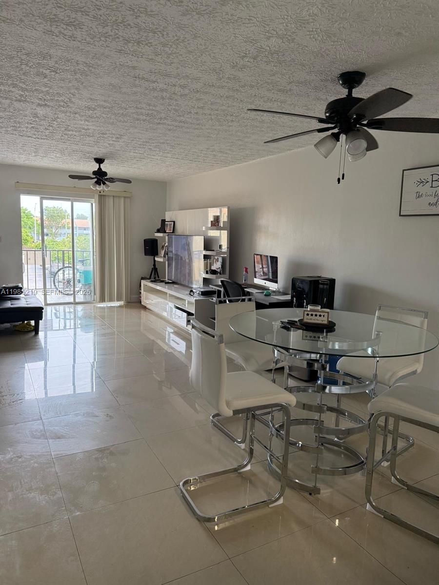 A living and dining area features white tile floors, a glass table, and a balcony view — 6055 W 19th Ave # 311, Hialeah FL 33012, HIALEAH, FL
