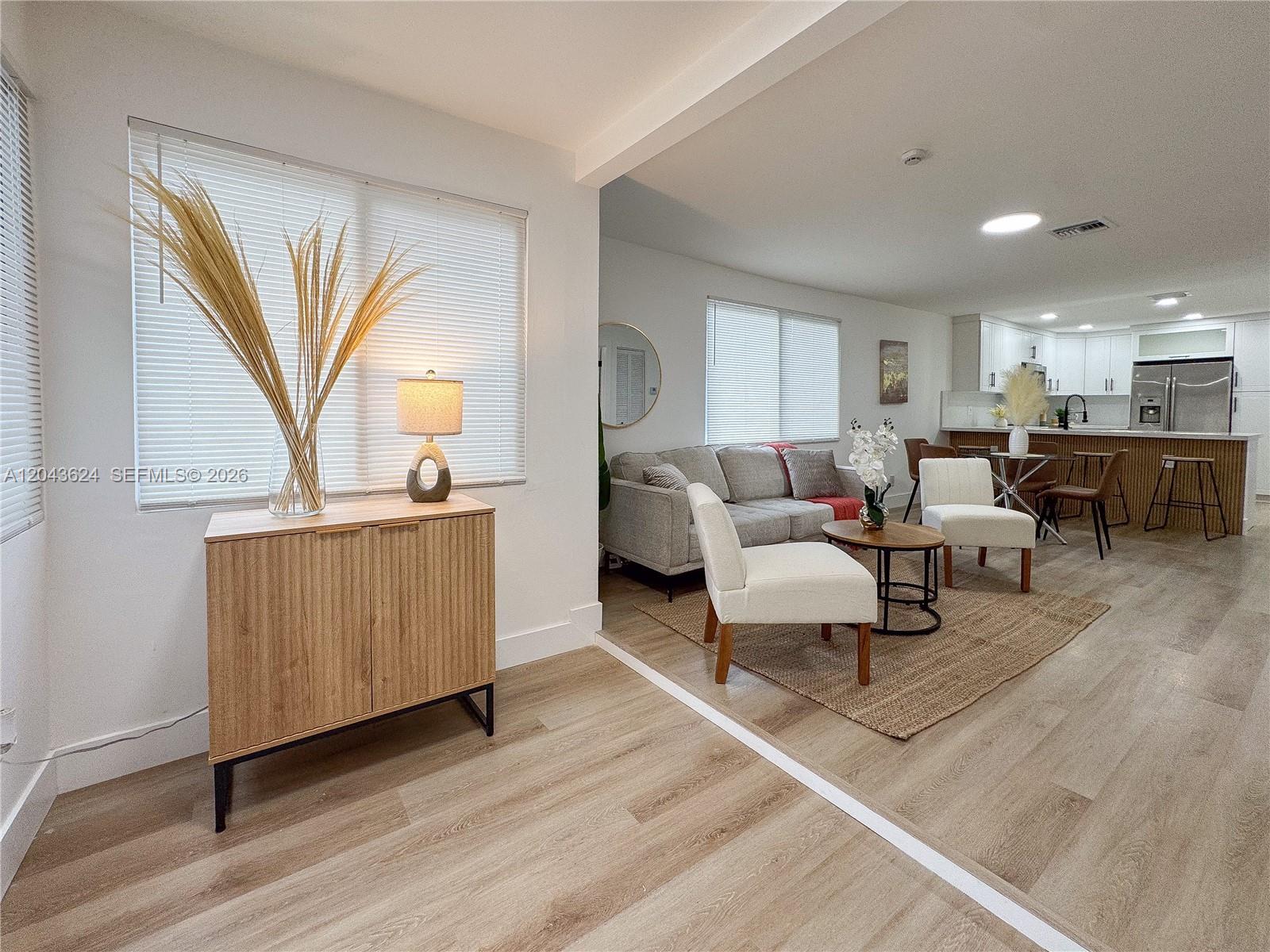An open-concept living area features light wood flooring, a neutral color palette, and modern furnishings — 1369 NW 68th Ter, Miami FL 33147, MIAMI, FL