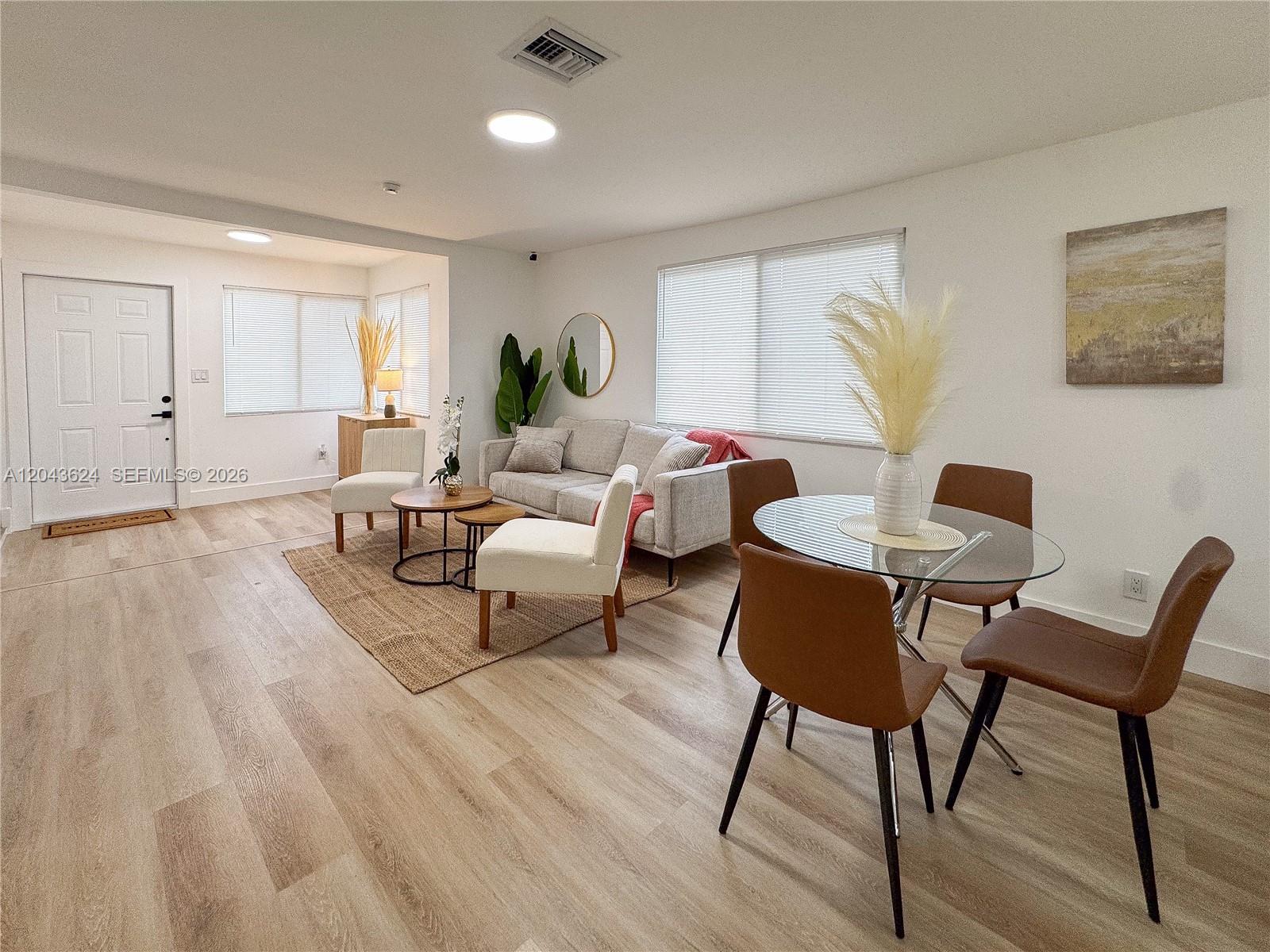 A living and dining area features light wood flooring, a sofa, and a glass table — 1369 NW 68th Ter, Miami FL 33147, MIAMI, FL
