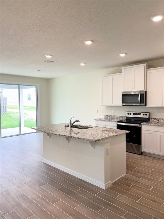 A kitchen with white cabinets, granite countertops, a center island, and wood-look tile flooring — 1336 NW 132ND CIRCLE, NEWBERRY, FL