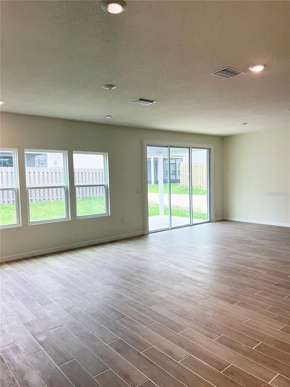 An empty living area features wood-look tile flooring, recessed lighting, and sliding glass patio doors — 1336 NW 132ND CIRCLE, NEWBERRY, FL