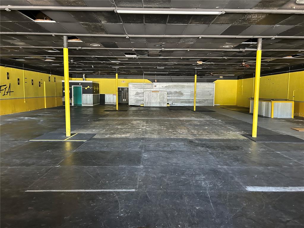 An empty commercial space features yellow walls, a black ceiling, and several yellow support columns — 2913 NE JACKSONVILLE ROAD, OCALA, FL