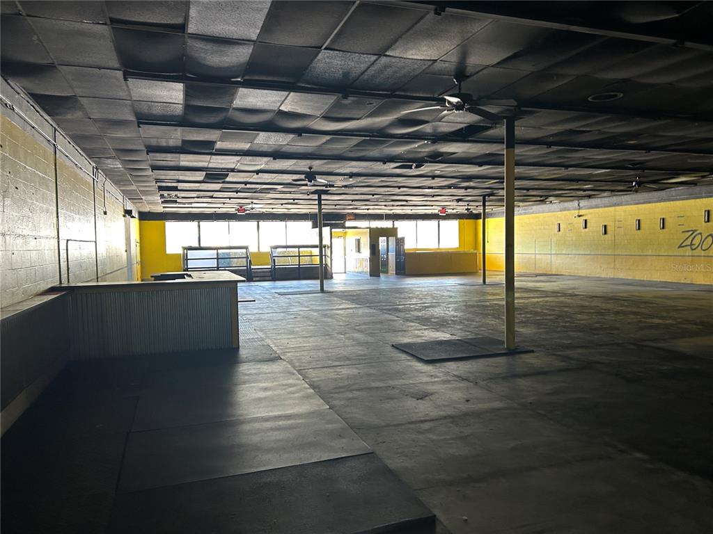 An empty commercial space features a black drop ceiling, yellow walls, and concrete flooring — 2913 NE JACKSONVILLE ROAD, OCALA, FL