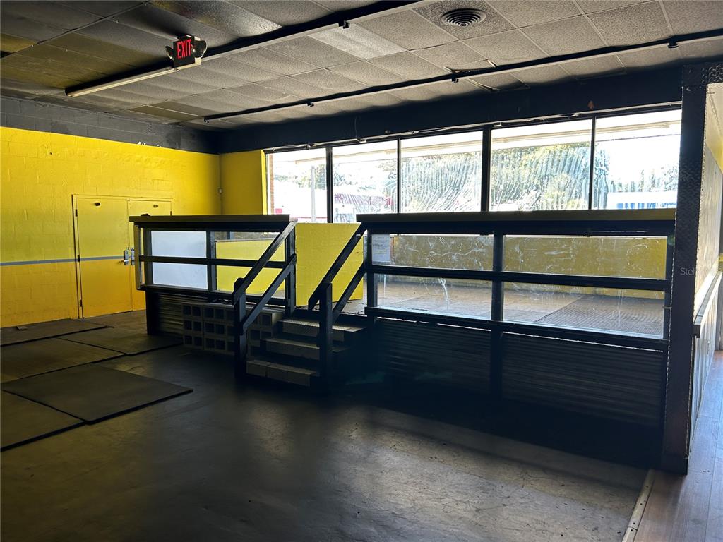 An interior view of a commercial space featuring yellow walls, a raised platform, and windows — 2913 NE JACKSONVILLE ROAD, OCALA, FL
