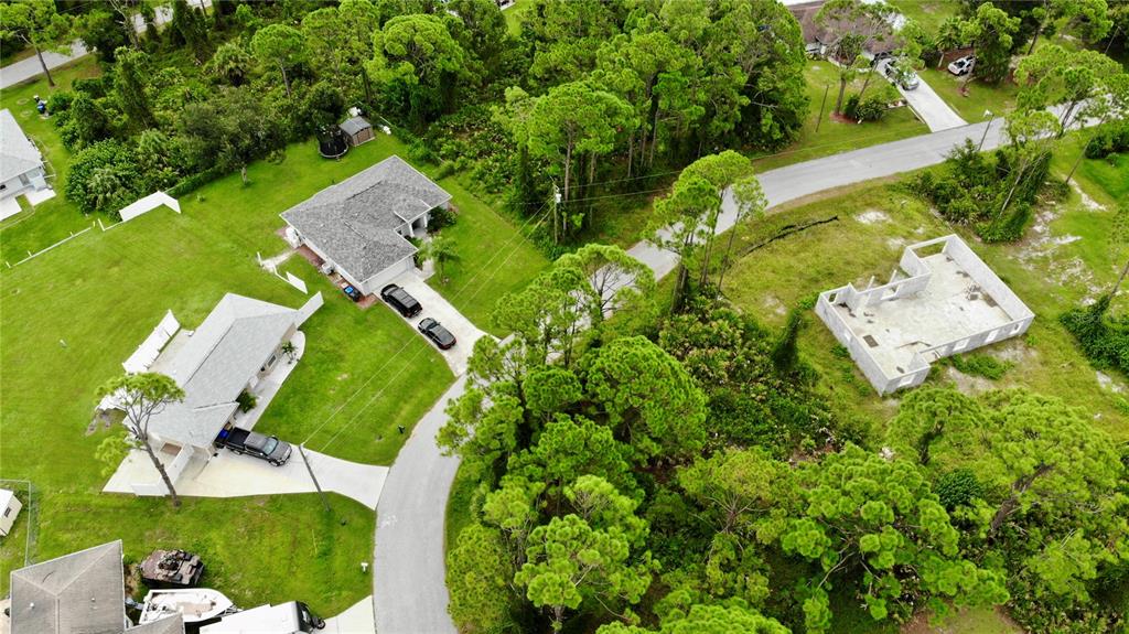 An aerial view shows several houses, a concrete foundation, and wooded areas along a road — TALLY HO ROAD, NORTH PORT, FL