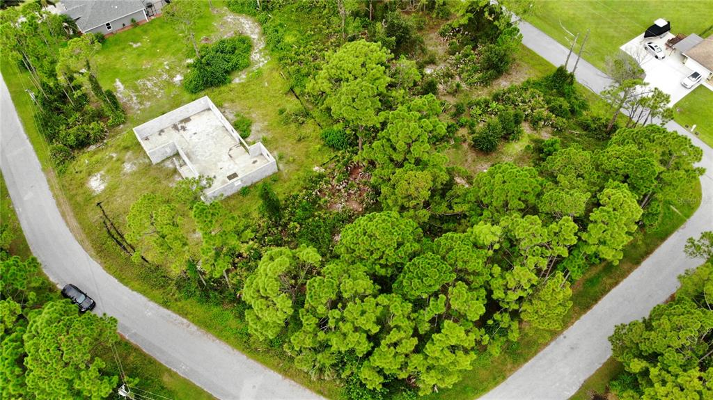 An aerial view shows a concrete foundation on a wooded lot between two paved roads — TALLY HO ROAD, NORTH PORT, FL