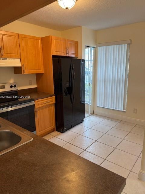 A kitchen features light wood cabinets, a black refrigerator, and a tiled floor — 2856 Cambridge Ln # 2856, Cooper City FL 33026, COOPER CITY, FL