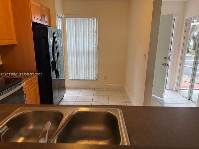A kitchen with a double-basin sink, wooden cabinets, a black refrigerator, and tile flooring — 2856 Cambridge Ln # 2856, Cooper City FL 33026, COOPER CITY, FL