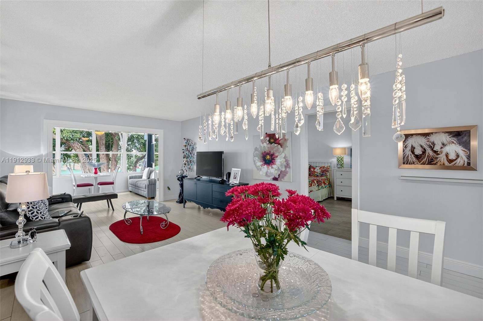 A dining area with a crystal chandelier overlooks a living room with a red rug — 7817 Golf Circle Dr # 305, Margate FL 33063, MARGATE, FL