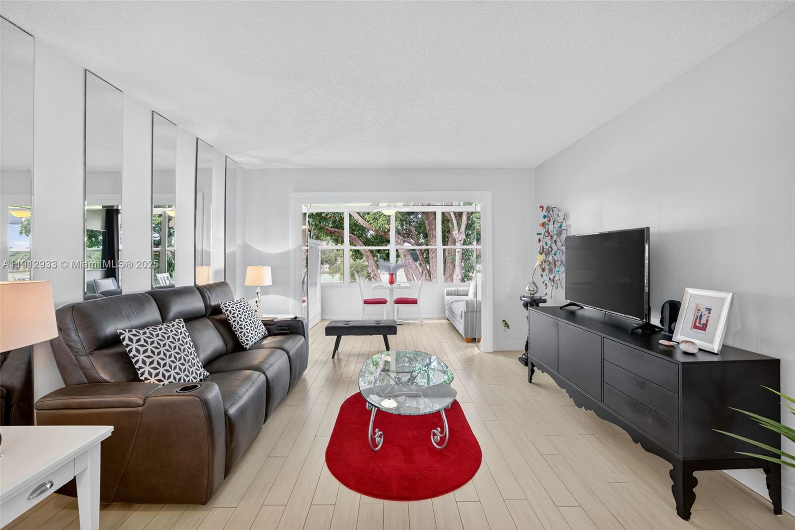 A living room features a dark leather sofa, a glass coffee table, and light flooring — 7817 Golf Circle Dr # 305, Margate FL 33063, MARGATE, FL