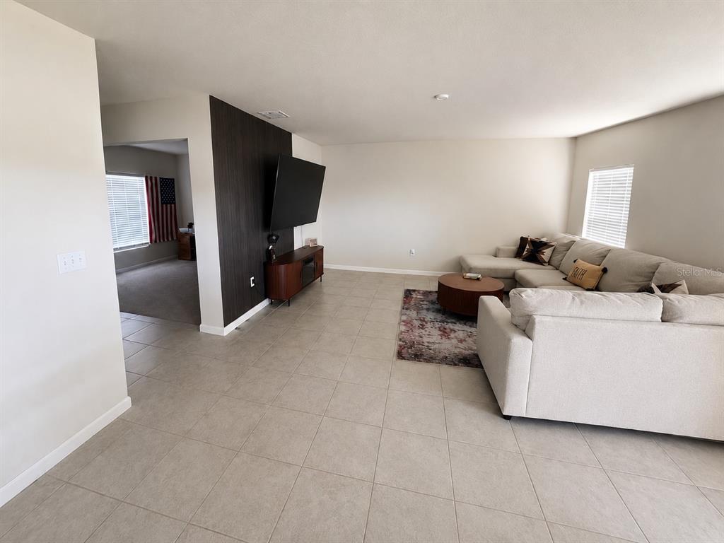A living room features light tile floors, a dark wood accent wall, and a sectional sofa — 614 MANCHESTER PATH, DUNDEE, FL
