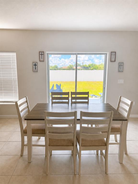 A dining room features a wooden table with six chairs and a sliding glass door — 614 MANCHESTER PATH, DUNDEE, FL