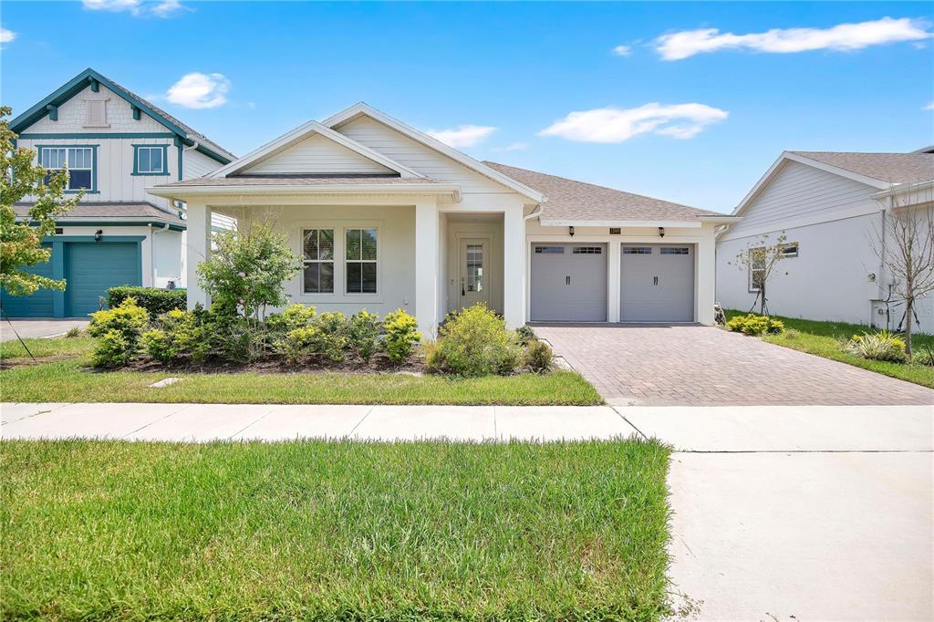 A single-story house with a white exterior, a front porch, and a two-car garage — 13589 MCMILLAN DRIVE, ORLANDO, FL