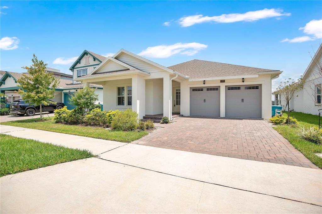 A single-story house with a brick driveway, two-car garage, and a covered front porch — 13589 MCMILLAN DRIVE, ORLANDO, FL