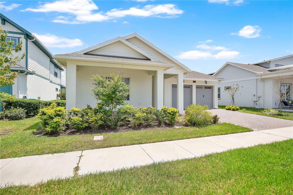 A single-story house with a covered porch, two-car garage, and a paved driveway — 13589 MCMILLAN DRIVE, ORLANDO, FL