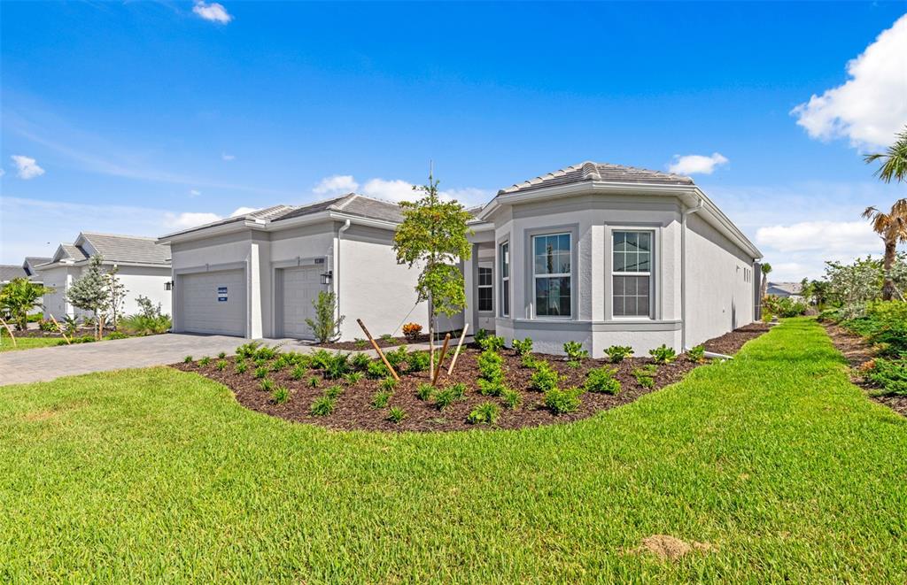 A single-story house with a gray exterior, a two-car garage, and a landscaped front yard — 26537 SANDY HILL CIRCLE, ENGLEWOOD, FL