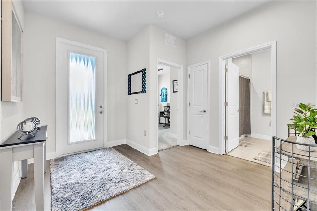 A bright entryway features light wood-look flooring, a glass-paneled front door, and several interior doors — 16239 S PORT HARBOR BOULEVARD, PORT CHARLOTTE, FL
