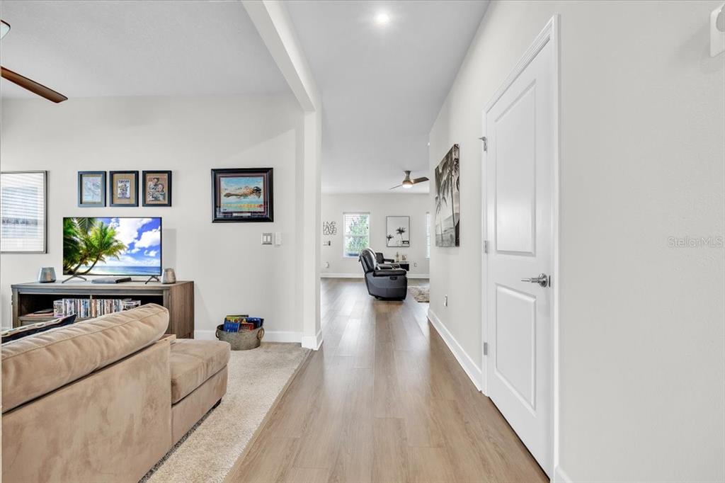 A living room with light wood flooring leads into a hallway toward another room — 16239 S PORT HARBOR BOULEVARD, PORT CHARLOTTE, FL