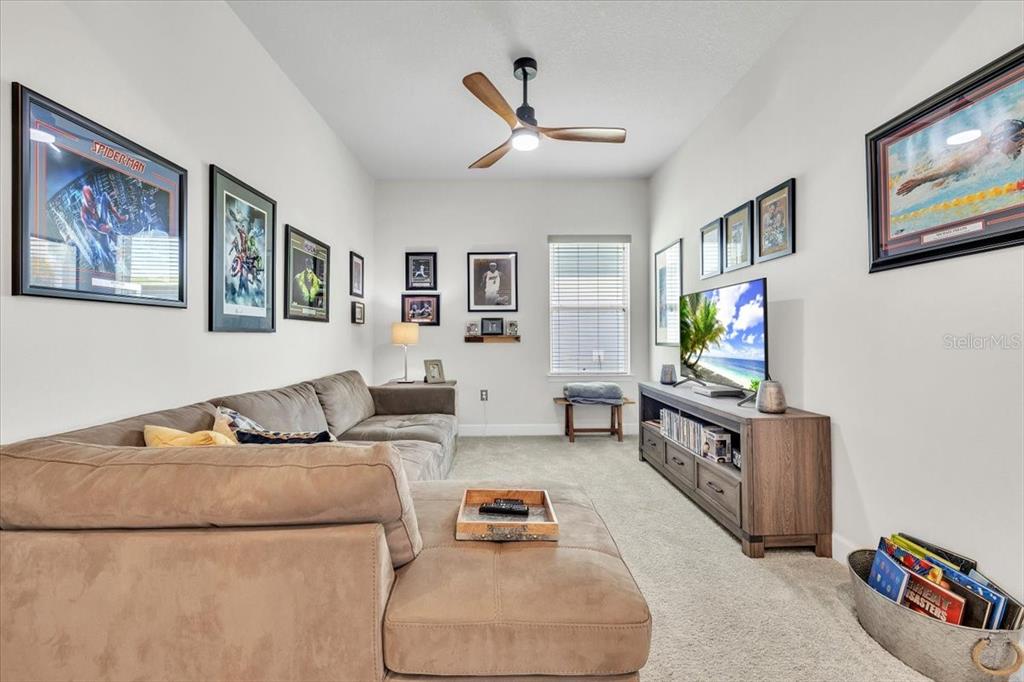 A living room features a large sectional sofa, a television on a console, and framed artwork — 16239 S PORT HARBOR BOULEVARD, PORT CHARLOTTE, FL