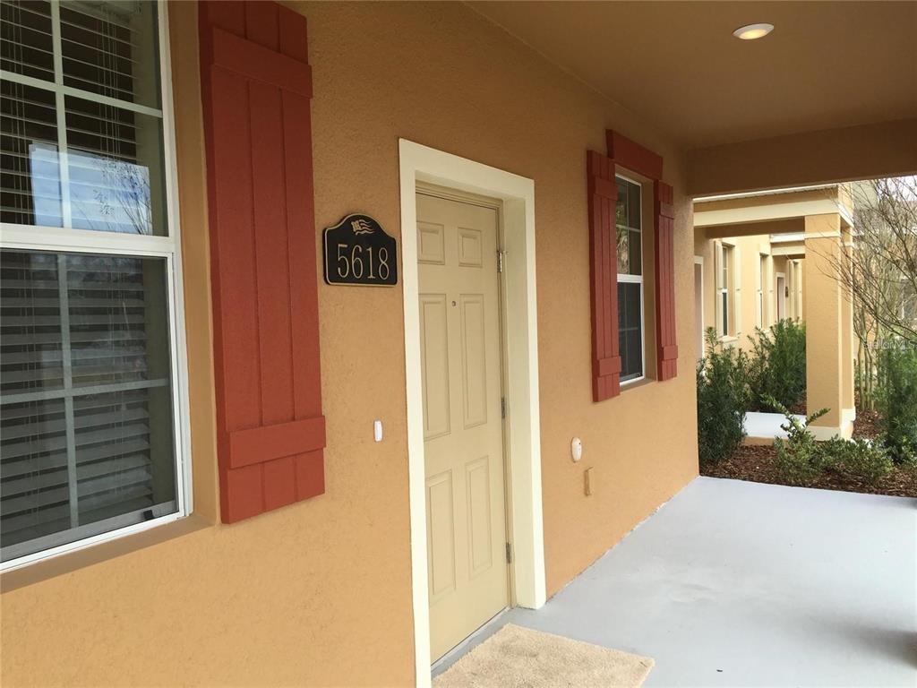 A tan house exterior features a front door, a window with red shutters, and address plaque — 5618 WATER ROSE ROAD, WINTER GARDEN, FL