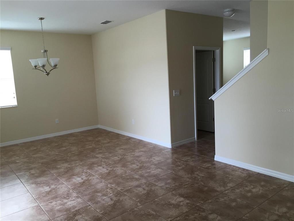 An empty room with tan walls, tile flooring, a chandelier, and a staircase — 5618 WATER ROSE ROAD, WINTER GARDEN, FL