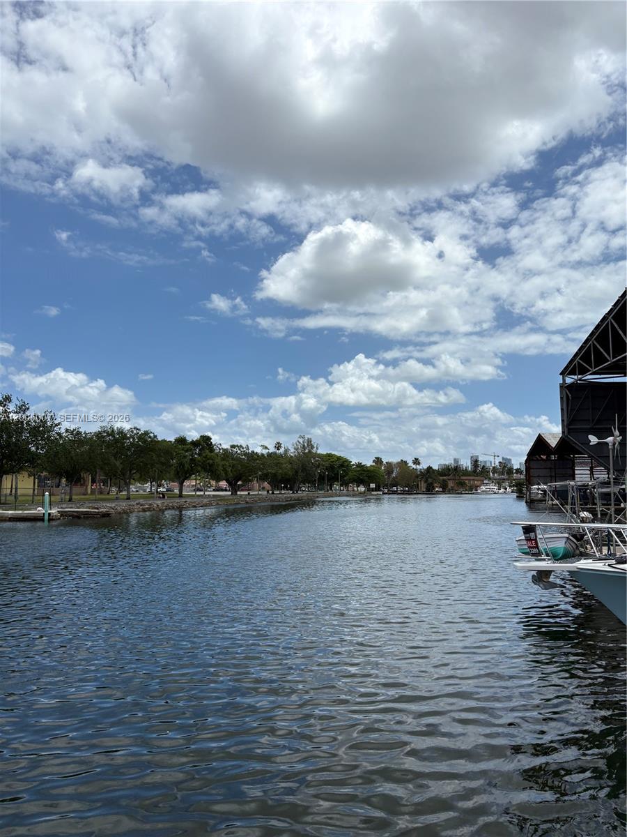 A view of a canal with boats docked on the right and trees lining the shore — 2415 NW 16th St Rd #11, Miami FL 33125, MIAMI, FL