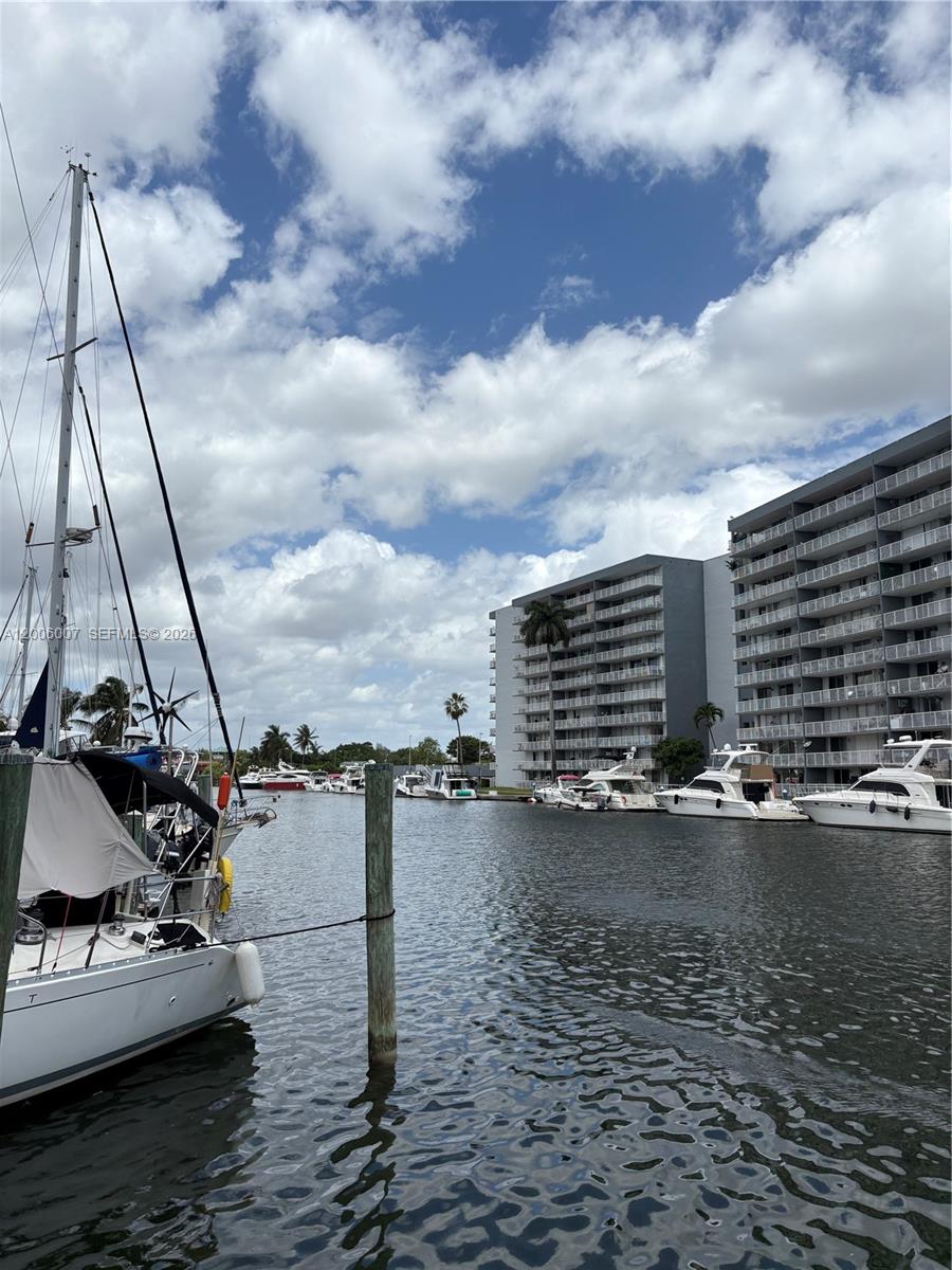 A canal view features several docked boats alongside large residential apartment buildings under a cloudy sky — 2415 NW 16th St Rd #11, Miami FL 33125, MIAMI, FL