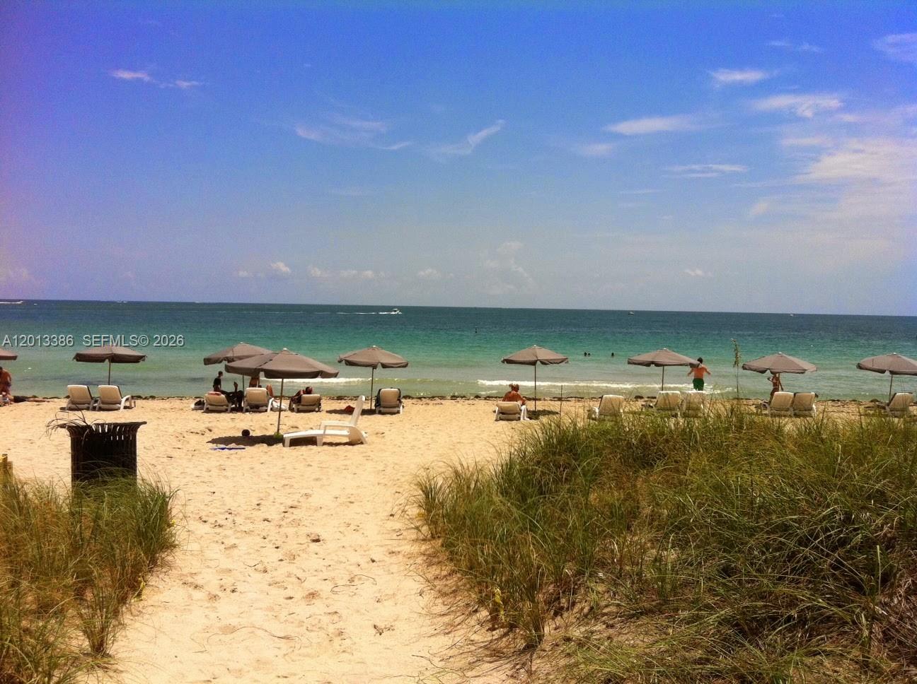 A sandy beach with umbrellas and lounge chairs overlooks the ocean under a blue sky — 10275 Collins Ave # 901, Bal Harbour FL 33154, BAL HARBOUR, FL