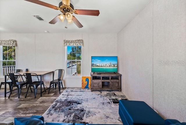 A living and dining area features a ceiling fan, a television, and wood-look flooring — 14428 STEPHENS ROAD, PORT CHARLOTTE, FL