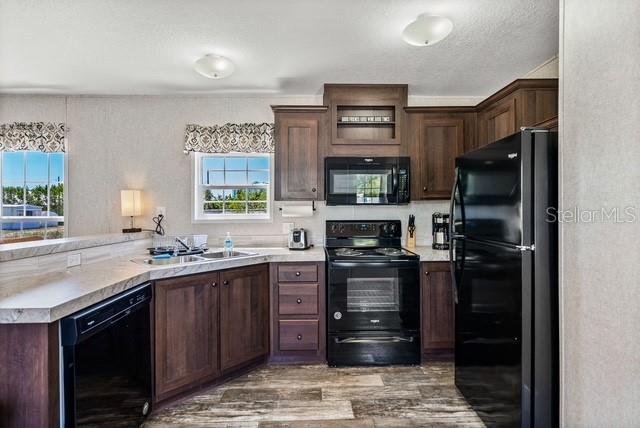 A kitchen features dark wood cabinets, black appliances, and a window above the sink — 14428 STEPHENS ROAD, PORT CHARLOTTE, FL