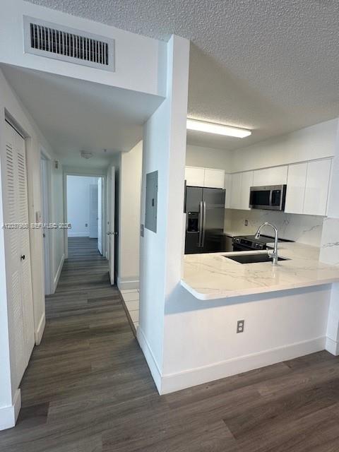 A kitchen with white cabinets and a marble countertop overlooks a hallway with wood flooring — 5091 NW 7th St # 1008, Miami FL 33126, MIAMI, FL