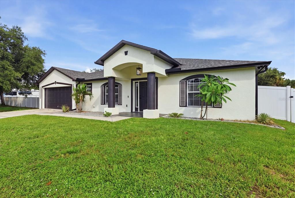 A single-story house with a white stucco exterior, dark trim, and a two-car garage — 281 PEMBROKE DRIVE, PORT CHARLOTTE, FL